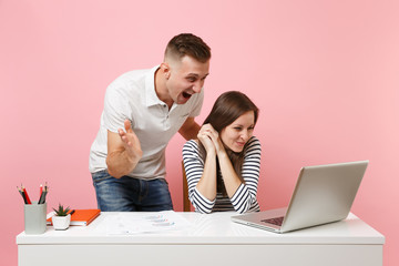 Two young smiling business woman man colleagues sit work at white desk with contemporary laptop isolated on pastel pink background. Achievement career concept. Copy space advertising, youth co working