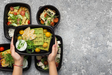Plastic containers with delicious food on gray background
