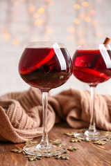 Glasses of delicious mulled wine with warm plaid on wooden table