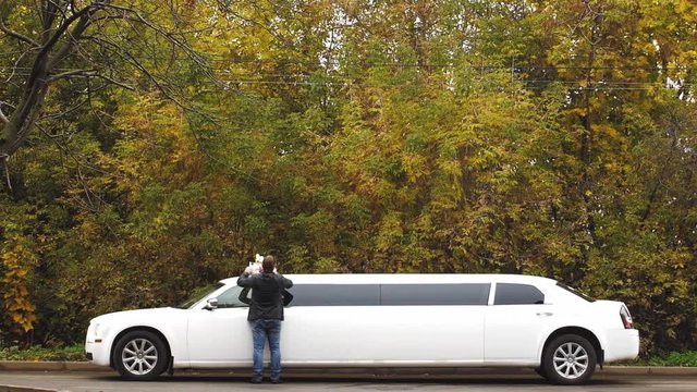 The man putting flowers on the top of white wedding limo