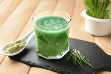 Glass of wheat grass juice with powder on slate plate