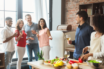 Multiethnic group of friends sharing good time in kitchen