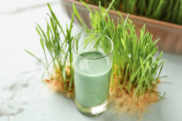 Shot of healthy juice with sprouted wheat grass on light table