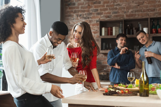 Excited Friends Drinking And Laughing In Kitchen