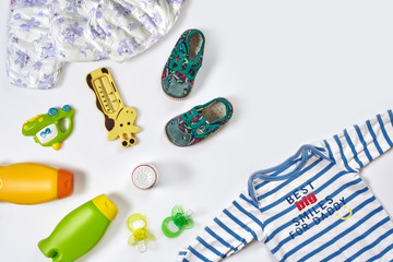Baby care accessories and clothing on white background, top view