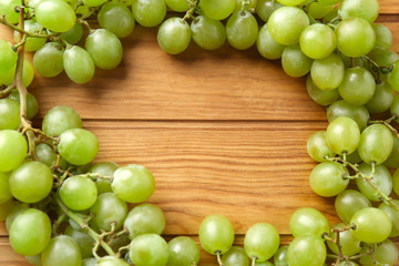 Frame made of ripe sweet grapes on wooden background