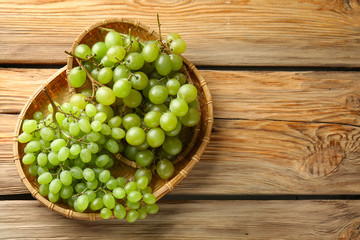 Plate with ripe sweet grapes on wooden background