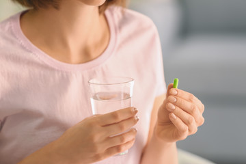 Woman with pill and glass of water, closeup