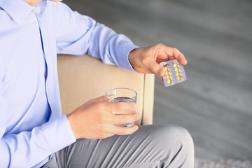 Man with pills and glass of water at home