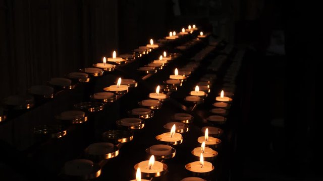 Rows of prayer candles burn in darkened cathedral