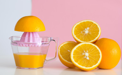 Freshly squeezed orange juice and orange on pink background. Health cocept.