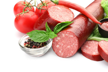 Delicious smoked sausages with spices and vegetables on white background