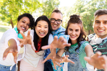people, friendship and international concept - group of happy smiling friends having fun in park