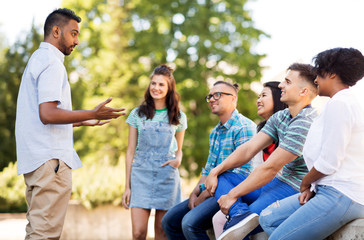 people, friendship and international concept - group of happy friends talking in park