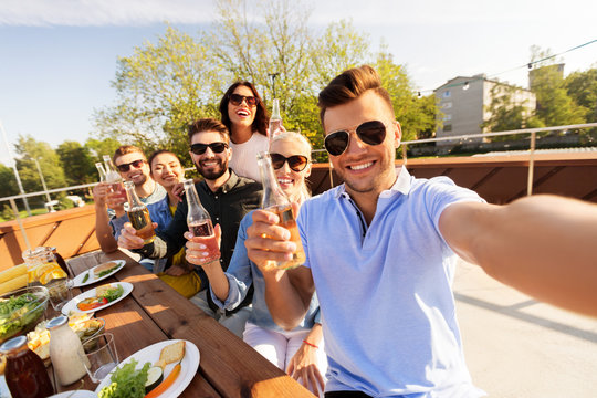 leisure and people concept - happy friends having bbq party on rooftop in summer and taking selfie