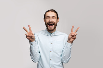Fototapeta premium Happy cheerful office employee man in stylish glasses, casual shirt, white background, shows a funny gesture, everything cool, he likes the weekend. Website image and advertising photo isolate.