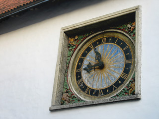 Fototapeta na wymiar Europe. The wall with old clock. The sun and the sky are on the clock face. The medieval ornament is on the clock. 