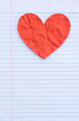 Red heart on white lined sheet of notepad with copy space