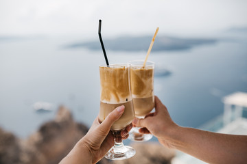 Two hands with two glasses of greek cold coffee