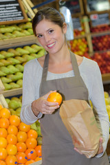 Obraz premium Portrait of shop assistant holding orange and paper bag