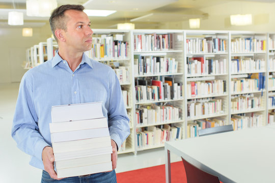 man carrying a pile of books