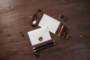 Blank paper envelope with wax seal and stationery on wood table background. Flat lay.