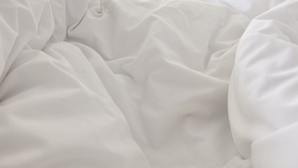 close up top view of white pillow on bed and with wrinkle messy blanket in bedroom, from sleeping...