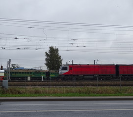 Pair of Two Red And Green Locomotives Trains On The Railroad Railway Behind Asphalt City Road And Grass