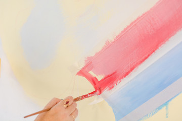 Woman paints with bright paints on a white wall