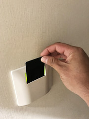 Hand using security key card scanning to open the electric system of building.