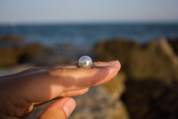 pearl in a hand against the background of the sea