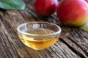 A bowl of apple cider vinegar with apples in the background