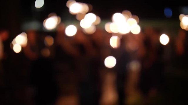 people waving sparklers celebrating new years blurred