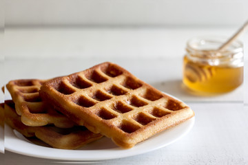 Viennese, Belgian waffles with honey on a white plate.