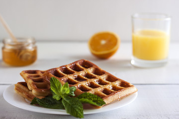 Viennese, Belgian waffles with honey on a white plate.