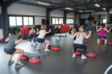 group of people exercising with bars in gym