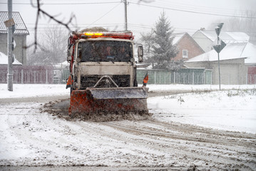 Snowblower cleans the road in the city during a snowstorm. Selective focus.