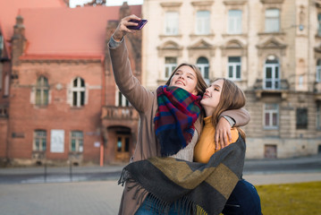 Obraz na płótnie Canvas Close up lifestyle portrait of two pretty fresh hipster young teenage girls. Best friends girls,make selfie and having fun. Cute pretty girls making funny selfie on the street, having fun together. 