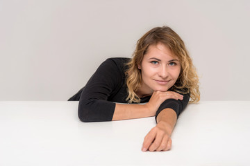 Portrait of a beautiful blonde girl on a white background at the table.