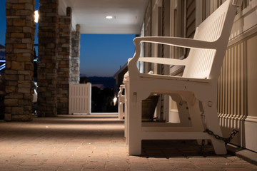 White wooden bench outside a hotel on the sidewalk near the harbor in Bristol Rhode Island.