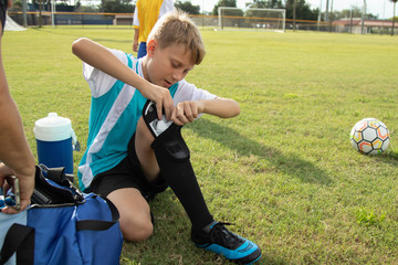 A soccer player puts on his shin guards. 
