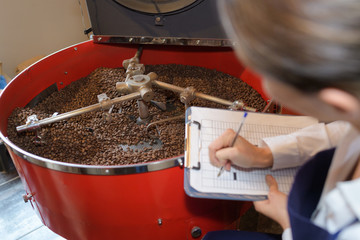 lady with clipboard checking coffee beans in vat