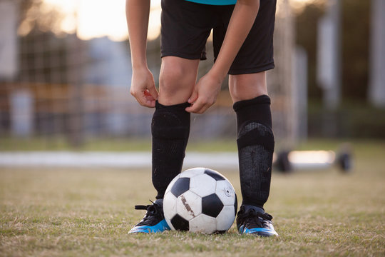 A soccer player adjusting his socks. 