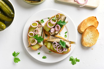 Sandwiches with sprats, marinated cucumber and onion
