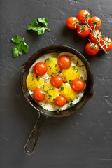 Fried eggs with tomatoes in frying pan
