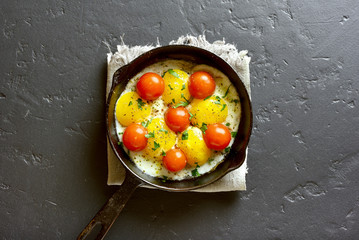 Fried eggs with tomatoes in frying pan