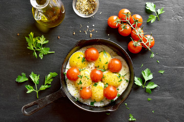 Fried eggs with tomatoes in frying pan