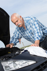 older man checking levels and servicing his car