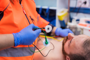 Emergency doctor hands, attaching ecg electrodes on patient chest in ambulance © herraez