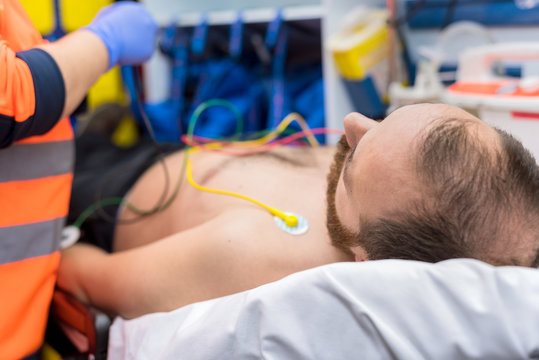 Emergency doctor hands, attaching ecg electrodes on patient chest in ambulance